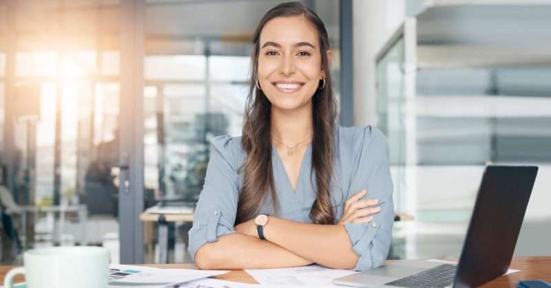 a woman smiles while sitting at a desk in the workplace