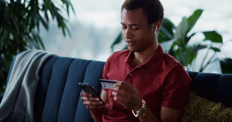 a young man in a red shirt makes a transaction on his phone