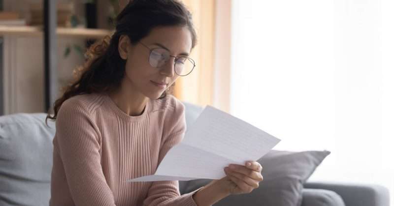 a young woman in glasses reads a letter from the mail