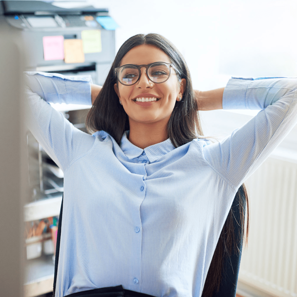 woman relaxes at a desk with her hands behind her head